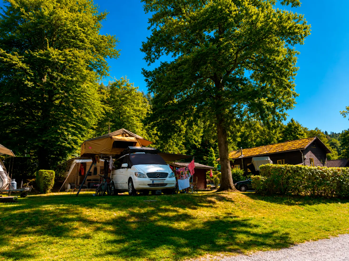 Campervan with roof tent on a pitch at Camping La Lienne